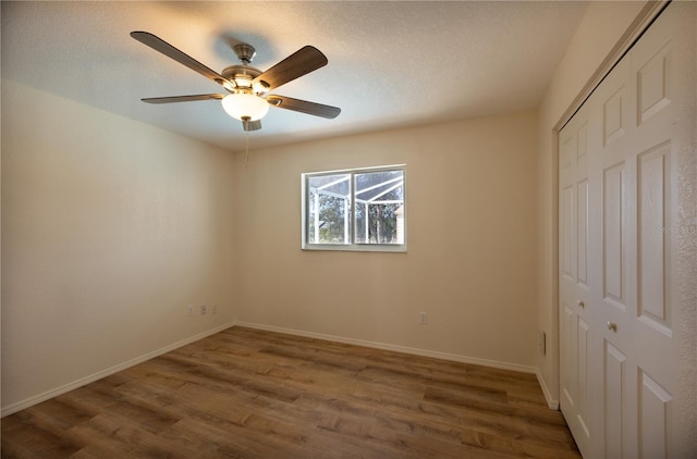 unfurnished bedroom featuring ceiling fan, a textured ceiling, dark hardwood / wood-style flooring, and a closet