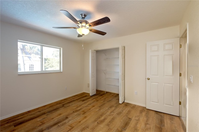 unfurnished bedroom with ceiling fan, a closet, a textured ceiling, and light wood-type flooring