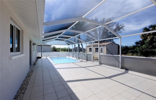 view of swimming pool with a storage unit, a patio area, and glass enclosure