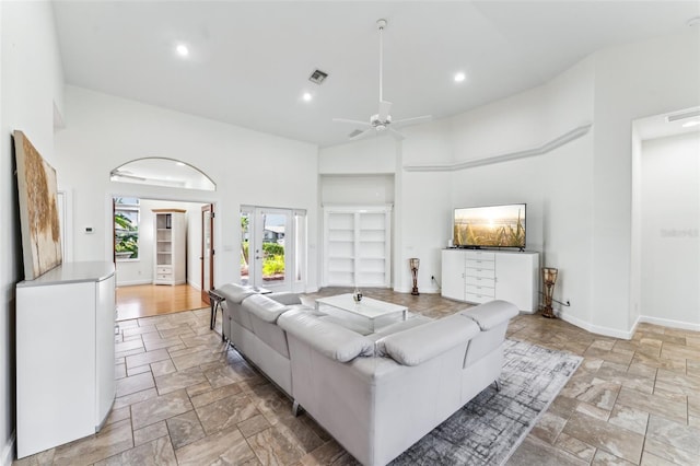 living room with french doors, ceiling fan, and a high ceiling