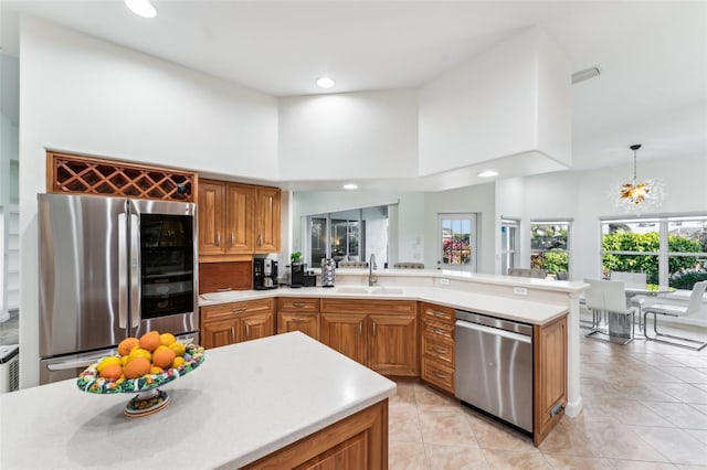 kitchen with sink, decorative light fixtures, light tile patterned floors, a towering ceiling, and stainless steel appliances