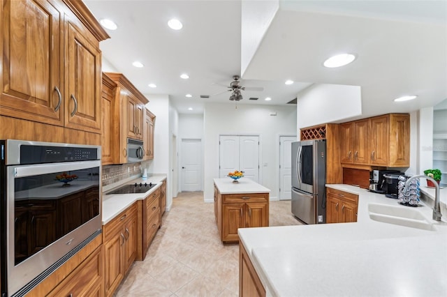 kitchen featuring sink, light tile patterned floors, appliances with stainless steel finishes, a center island, and decorative backsplash