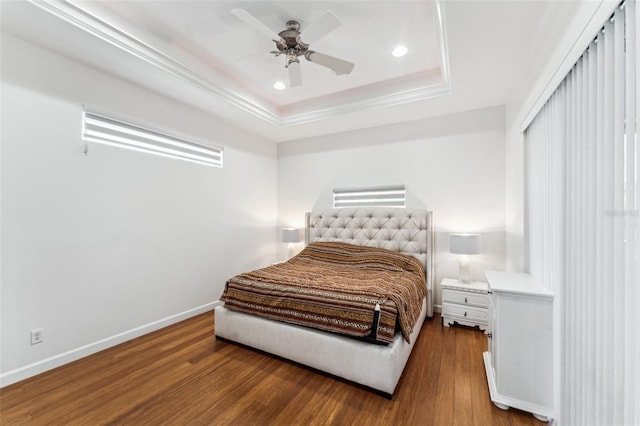 bedroom with hardwood / wood-style floors, ceiling fan, and a tray ceiling