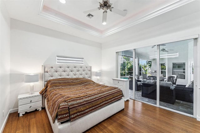 bedroom featuring dark hardwood / wood-style flooring, access to outside, and a raised ceiling