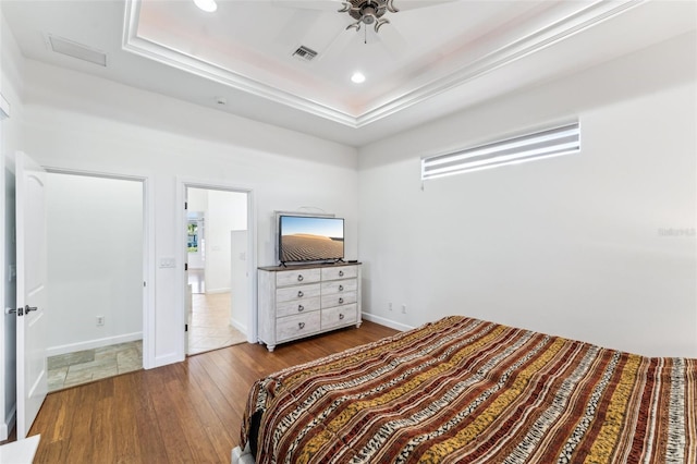 bedroom with wood-type flooring, ceiling fan, and a tray ceiling