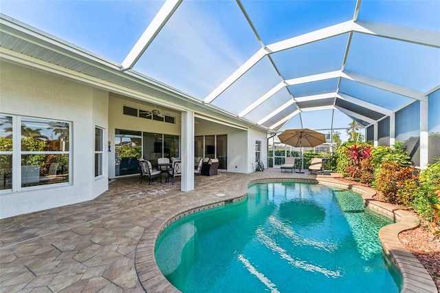 view of swimming pool with ceiling fan, outdoor lounge area, a patio area, and glass enclosure