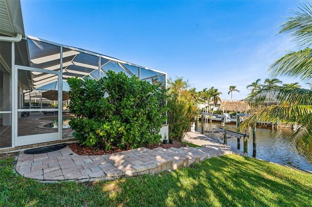 view of yard featuring a water view, a lanai, and a dock