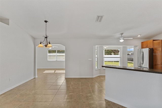 interior space with light tile patterned flooring, ceiling fan with notable chandelier, and a textured ceiling