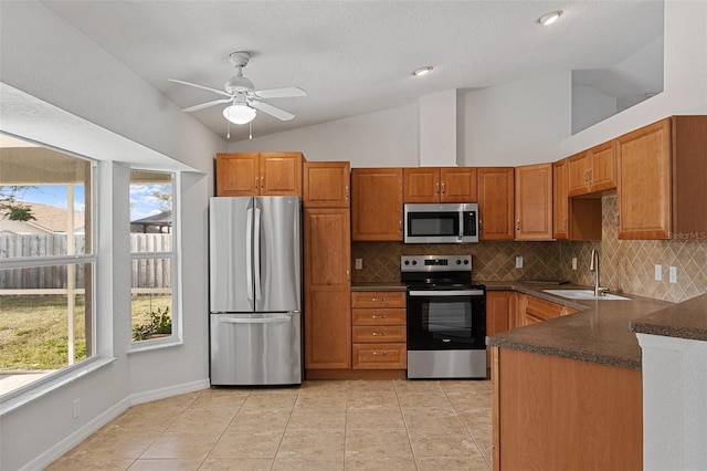 kitchen with lofted ceiling, sink, appliances with stainless steel finishes, light tile patterned flooring, and kitchen peninsula