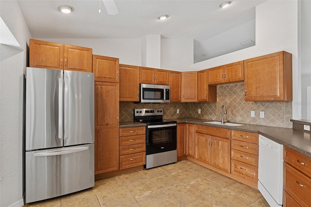 kitchen featuring lofted ceiling, sink, light tile patterned floors, appliances with stainless steel finishes, and decorative backsplash