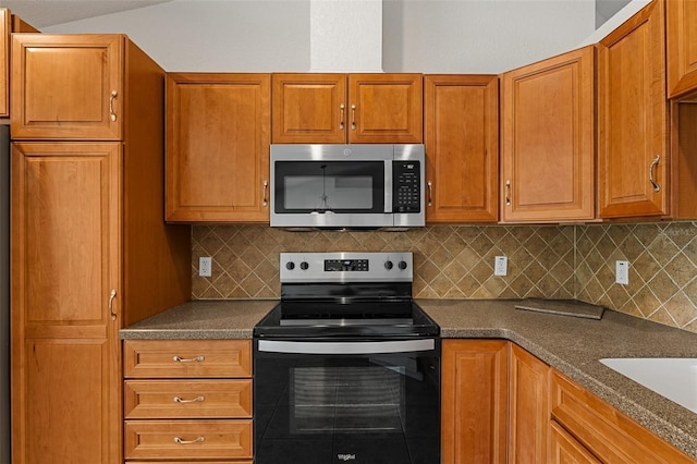 kitchen with backsplash, appliances with stainless steel finishes, sink, and dark stone countertops