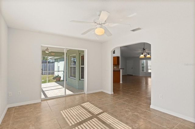 empty room with tile patterned flooring and ceiling fan with notable chandelier