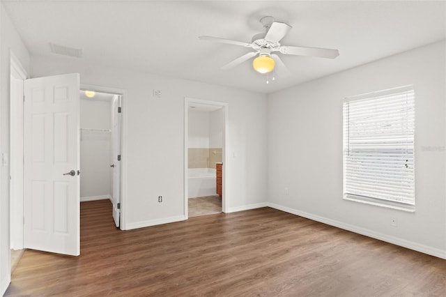 unfurnished bedroom with dark hardwood / wood-style floors, connected bathroom, a walk in closet, ceiling fan, and a closet