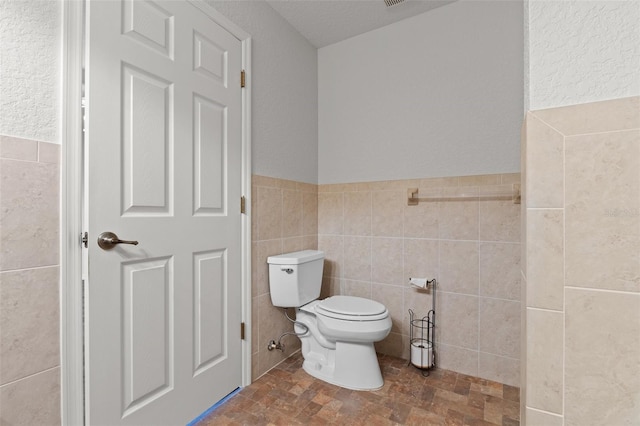 bathroom featuring tile walls and toilet