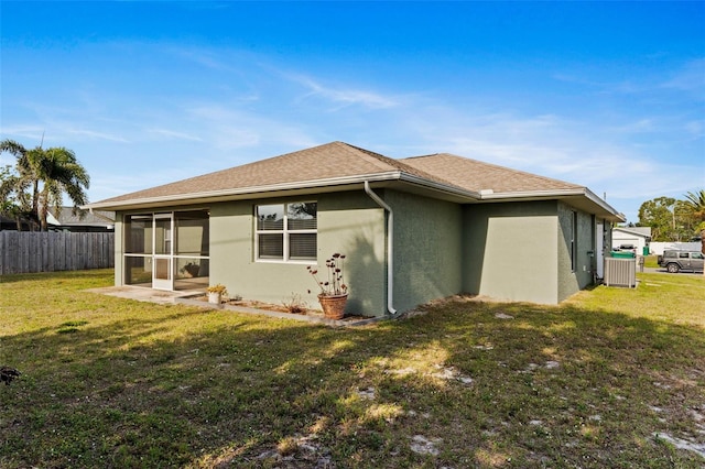 rear view of property with a sunroom, a yard, and central AC unit