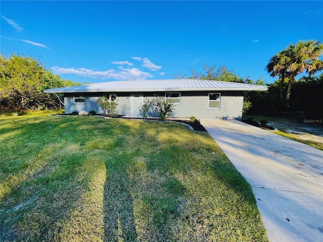 ranch-style house with metal roof, a front yard, and stucco siding