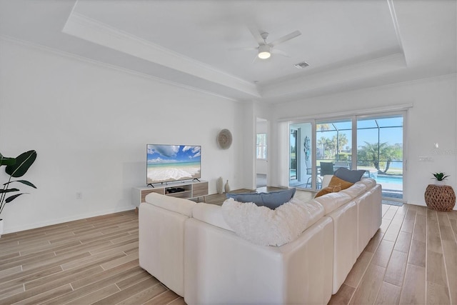 living room with crown molding, a tray ceiling, and ceiling fan