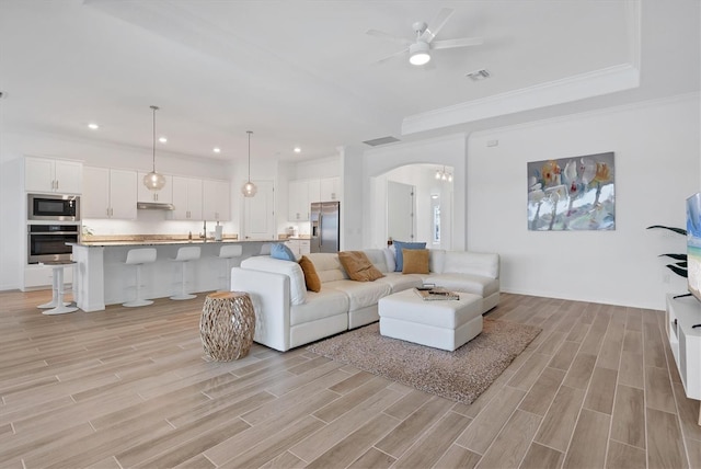 living room featuring a raised ceiling, crown molding, and ceiling fan