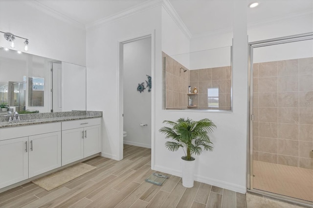 bathroom featuring crown molding, tiled shower, vanity, and toilet