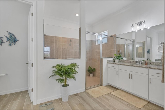 bathroom with crown molding, vanity, and a shower with door