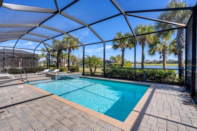 view of pool with an in ground hot tub, a water view, a patio area, and glass enclosure