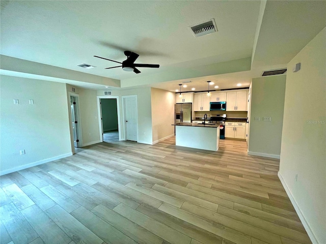 kitchen with stainless steel appliances, white cabinets, light wood-type flooring, and decorative light fixtures