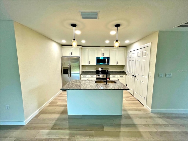 kitchen featuring stainless steel appliances, hanging light fixtures, sink, and white cabinets