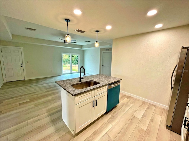 kitchen featuring appliances with stainless steel finishes, an island with sink, sink, white cabinets, and dark stone counters