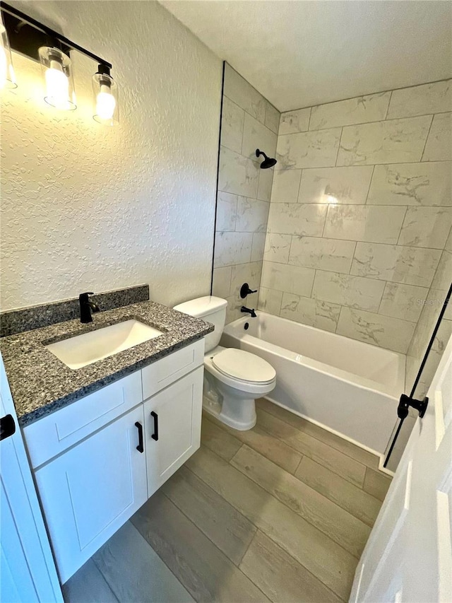 full bathroom with vanity, tiled shower / bath, hardwood / wood-style flooring, and toilet