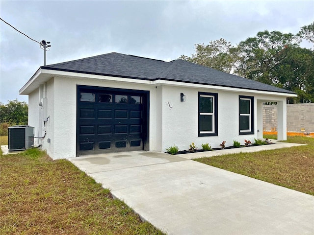 prairie-style home with a garage, a front yard, and central AC unit