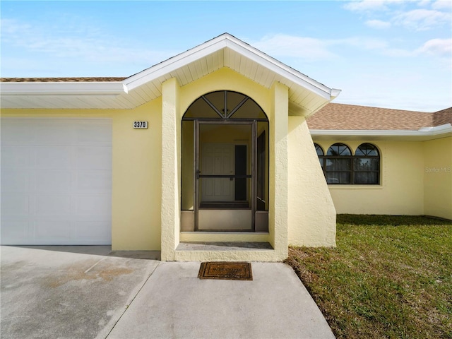 entrance to property with a garage and a lawn