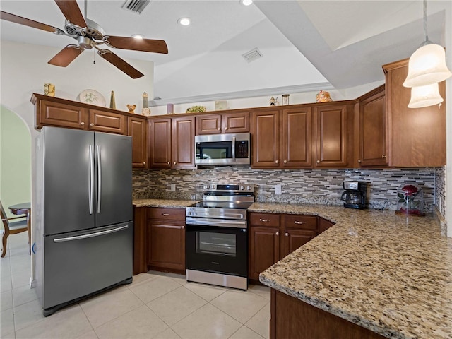 kitchen featuring light tile patterned flooring, appliances with stainless steel finishes, pendant lighting, decorative backsplash, and light stone countertops