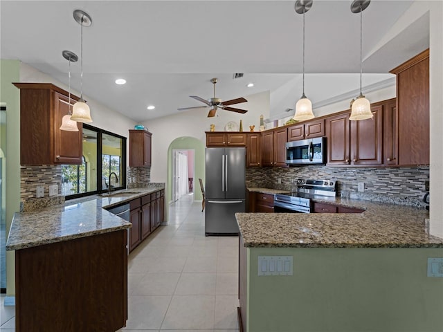 kitchen with sink, stone countertops, hanging light fixtures, kitchen peninsula, and stainless steel appliances