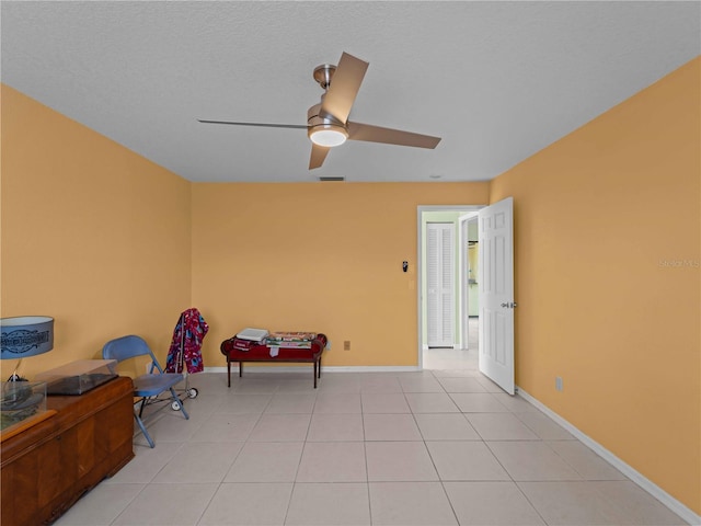 sitting room featuring ceiling fan, a textured ceiling, and light tile patterned floors