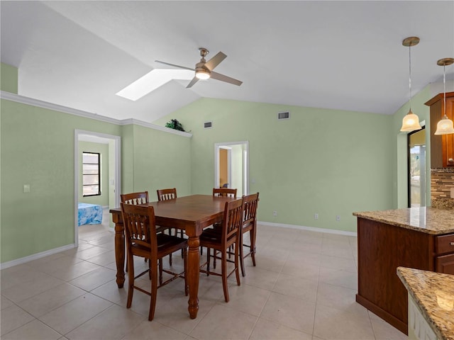 tiled dining space with vaulted ceiling with skylight and ceiling fan