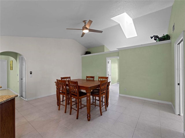 dining room with lofted ceiling with skylight, light tile patterned flooring, and ceiling fan