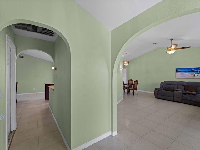 corridor featuring vaulted ceiling and light tile patterned floors