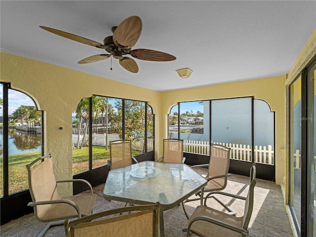 sunroom with a water view and ceiling fan