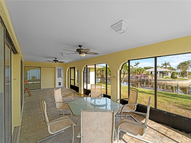 sunroom / solarium featuring a water view and ceiling fan