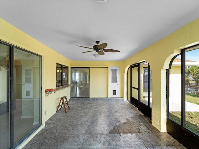 unfurnished sunroom featuring ceiling fan and a healthy amount of sunlight