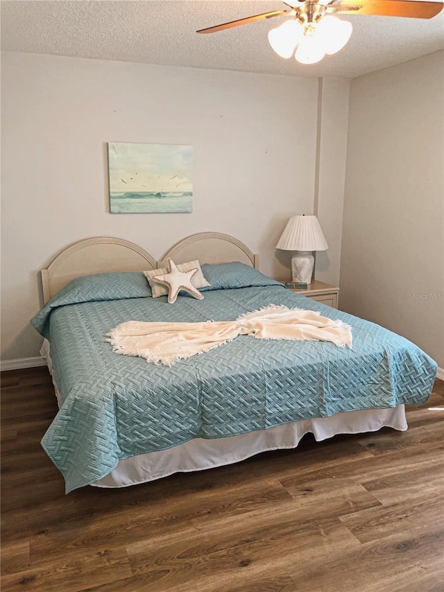 bedroom with a textured ceiling, a ceiling fan, and dark wood-type flooring