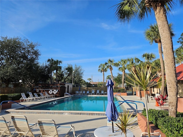 community pool with a patio area and fence