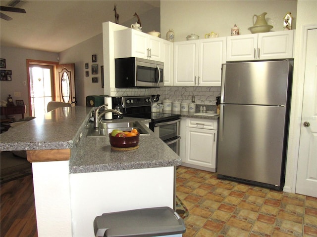 kitchen featuring lofted ceiling, appliances with stainless steel finishes, sink, and white cabinets