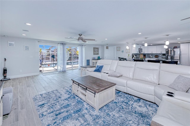 living room with light hardwood / wood-style flooring and ceiling fan