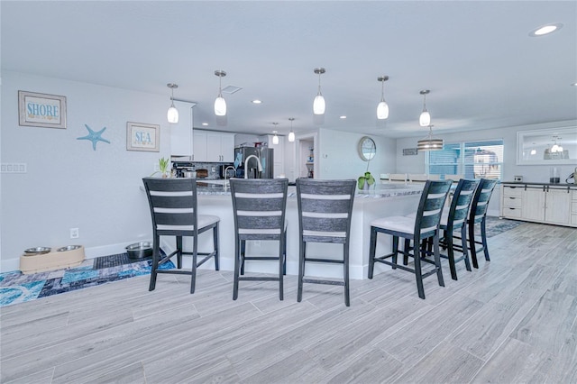 kitchen with hanging light fixtures, a breakfast bar area, white cabinets, and a spacious island