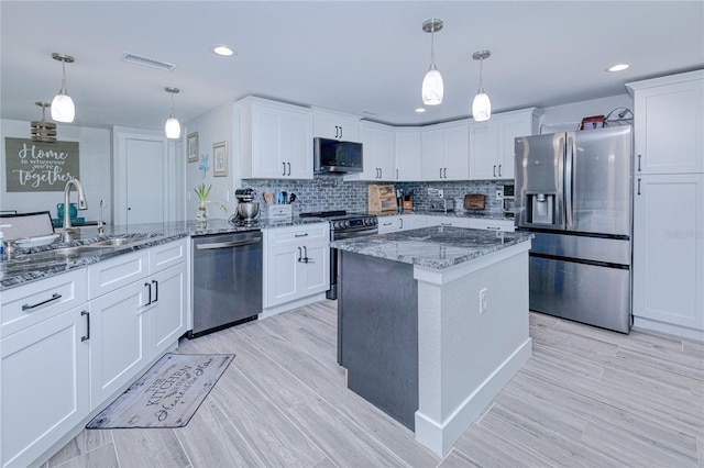 kitchen with pendant lighting, appliances with stainless steel finishes, kitchen peninsula, and sink