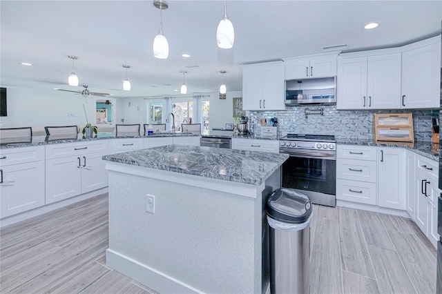 kitchen featuring appliances with stainless steel finishes, decorative light fixtures, white cabinets, a center island, and kitchen peninsula