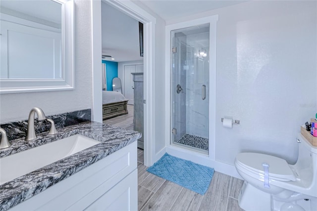 bathroom featuring a shower with door, vanity, and toilet