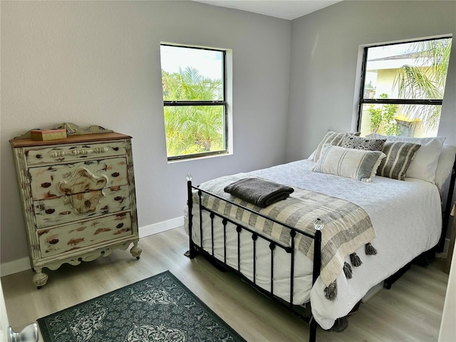 bedroom featuring multiple windows and light hardwood / wood-style flooring