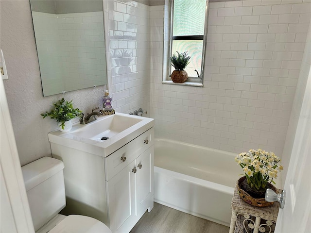 full bathroom featuring tiled shower / bath, vanity, toilet, and hardwood / wood-style floors